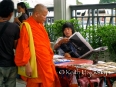 A monk shops at the Buddha amulet market - several blocks full of vendor stalls selling every sort of Buddha stone and amulet possible. copy